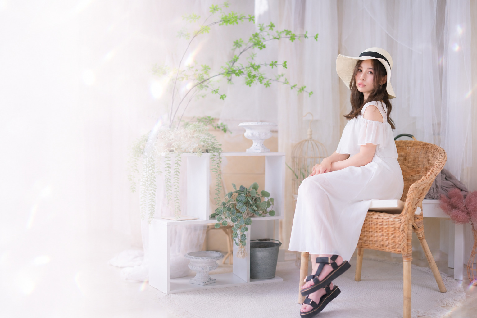 白いワンピースと帽子姿で椅子に座るKOYUKI